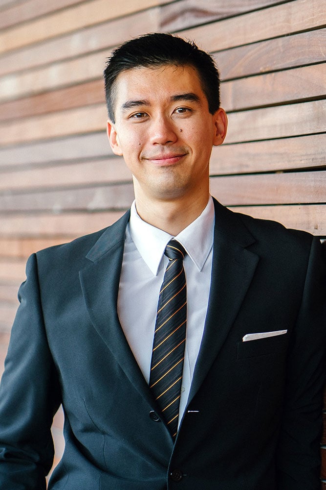 A man in a suit and tie standing against a wall.